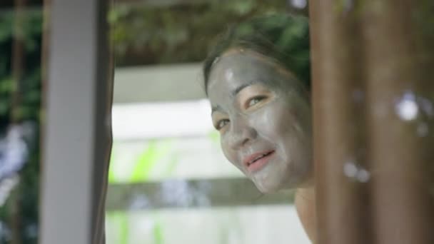 Młoda Dziewczyna Masce Kosmetycznej Twarzy Figlarnie Otwiera Zasłonę Okna Aby — Wideo stockowe