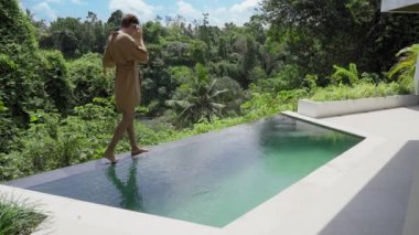 Bornozlu yakışıklı bir işadamı lüks bir havuz kenarında yürüyor ve güneşli bir günde telefonla konuşuyor. Başarılı bir adam pahalı bir spa otelinde dinlenir ve tatilde bile çalışır..