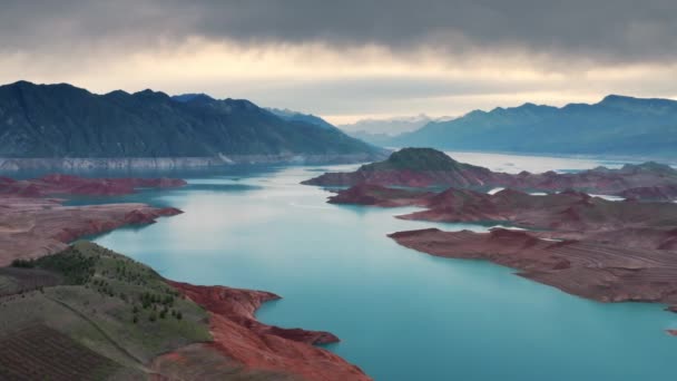 Aerial flight Beautiful spring landscape of river with blue turquoise water and hills against background of mountains and dawn sky. Bare rocky shores are visible due to ow water level on the lake. — Stock Video