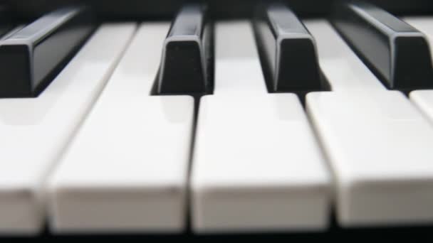 Närbild makro plan av svarta och vita pianotangenter. Kör längs pianotangenterna på ett vackert piano. Musikalisk syntes nycklar före konserten. Pianodelar. Långsamma rörelser. — Stockvideo