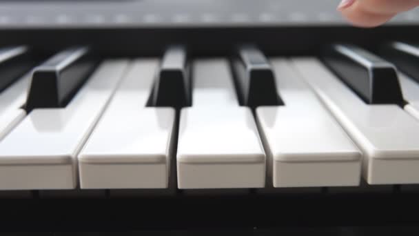 Une pianiste avec une manucure rose passe son doigt sur les touches blanches du piano. La fille passe deux doigts sur les clés d'un synthétiseur électronique. Macro. Au ralenti. Gros plan. — Video