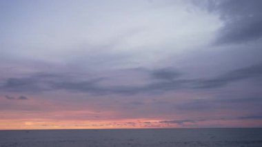Okyanustan gelen deniz manzarası, parlak turuncu bir gün batımı ve mor bir akşam gökyüzü. Bulutların geceye dönüştüğü eşsiz bir akşam havası. Endonezya Bali Adası