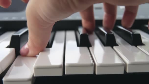 Närbild av fingrarna på en person med rosa manikyr som spelar en elektronisk synt. En ovanlig titt på tangenterna till pianot där kvinnan spelar musik. närbild. slow motion. docka. — Stockvideo