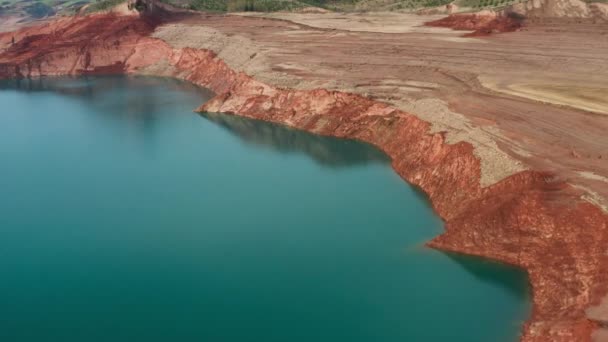 Un dron volando sobre un río con agua y una cantera de arena en el fondo de un valle verde con montañas y un cielo nublado. Maravilloso paisaje natural desde una vista de pájaro durante el día. 4k. — Vídeos de Stock