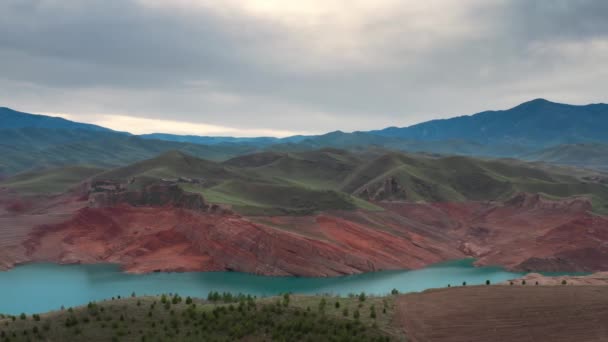 Turkuaz nehri üzerinde güzel bir dron uçuşu ve küçük su seviyesi nedeniyle kırmızı taştan kayalık kıyılar. Eşsiz vahşi yaşamın bahar manzarası. Altlarından sarkan yeşil tepeler ve kayalar — Stok video