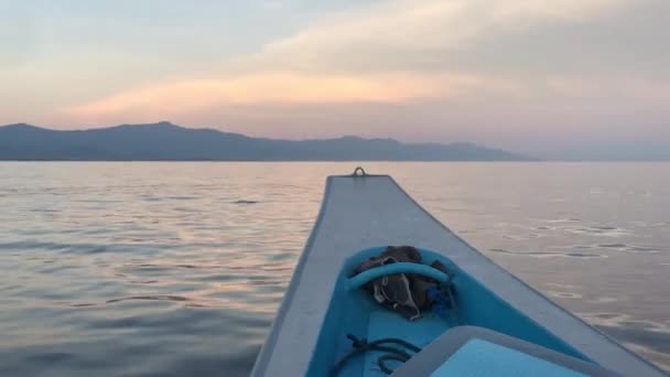 The nose of a blue and white boat sailing at dawn on the small waves of the ocean, against the backdrop of beautiful mountains in the fog. Unique views of the ocean and the beauty of Bali island. — стокове відео