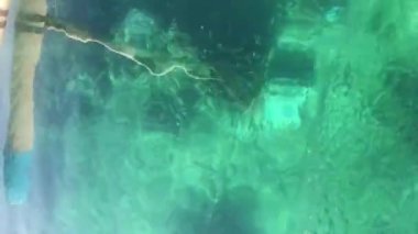 Okyanus mercanlarının sularında kristal berrak, şeffaf turkuaz sularda yüzen bir teknenin görüntüsü. Güneşli bir günde sualtı dünyası. Bali Endonezya. Suyun üzerinde beyaz köpük hızlı hareket eden tekneden