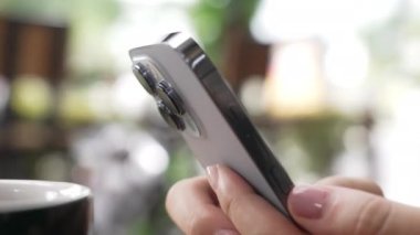 Hareketle çerçevele. Yeni moda modern Apple iPhone 13pro 'nun insan eliyle yakın çekimi. Kişi bir telefon tutuyor ve parmaklarıyla ekranda yazı yazıyor. Güzel Bokeh, güneşli bir günde.