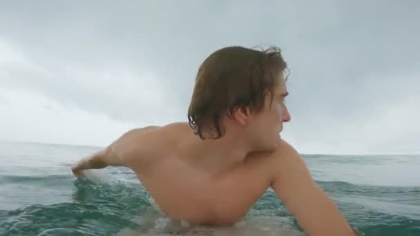 Un joven surfista remar la ola, comienza y monta la ola, pero la ola cae sobre él y lo golpea fuera de la tabla. Una gran ola golpea al surfista fuera de la tabla y cae al agua. Primer plano. — Vídeos de Stock