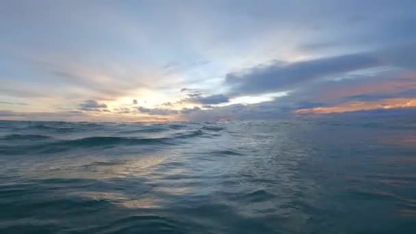 Nádherný přímořský mys Pov člověka v oceánu. Krásná krajina západu slunce se zelenými vlnami a obloha s mraky v krásných barvách, odstíny západu slunce. Střílení z vody a pocit přítomnosti — Stock video