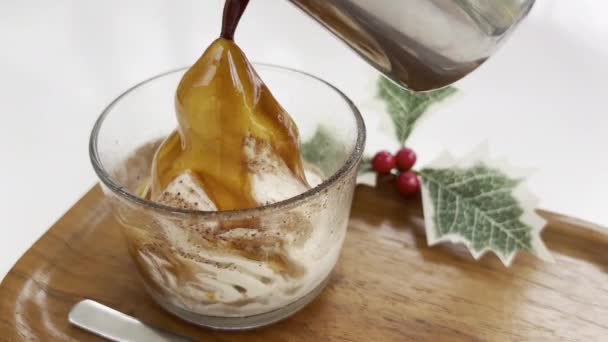 Nieuwjaarsaffogato. IJs in transparant glas in de vorm van besneeuwde berg waarop koffie wordt gegoten van boven het creëren van heerlijke drank. Op de achtergrond is Kerst hulst met rode bessen — Stockvideo