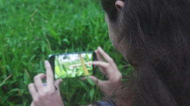 Gezgin bir kız telefonuyla bir video çekiyor, güzel yeşil çimenler gün içinde rüzgarda sallanıyor. Koyu renk uzun saçlı kadın blogcu video çekip telefonuyla fotoğraf çekiyor. Yavaş çekim