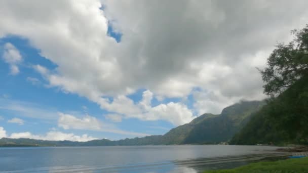 晴れた日には青い空に湖と緑の山々と白い雲が急速に浮かんでいる素晴らしい風景空を高速で移動する雲とボートと素晴らしい風景 — ストック動画