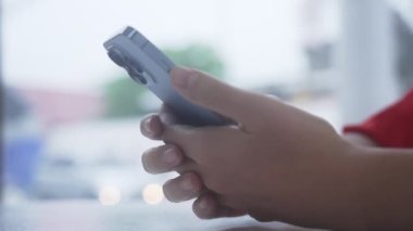 Yeni iPhone 13 profesyonel telefonunda, yoldan geçen arabalarla parlak caddenin arka planına karşı yazı yazan insanların yakın çekimleri. Blogcu kafede oturuyor ve sosyal ağların yavaş akışını izliyor
