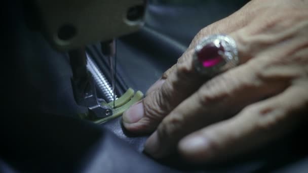 Close-up of old hands with silver ring of sewing master who make complicated seam on black skin jacket next to zipper. Penjahit menciptakan barang-barang kulit, jahitan garis sepanjang ritsleting. Gerakan lambat. — Stok Video