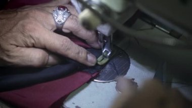 Karanlık bir atölyedeki bir ışık demetinde dikiş makinesinin üzerindeki deri cekete kahverengi astar diken yaşlı bir terzinin elleri. Mor taşlı, kocaman yüzüklü bir usta.