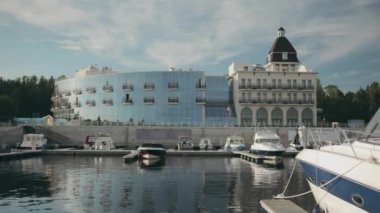 Modern sürat tekneleri ve yatları olan, cam paralel pencereli, kulesi ve marinası olan büyük, güzel, modern bir yat kulübü. Yat kulübünün manzarası Gün batımında altın ışık.