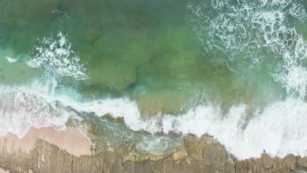 Vista superior del poderoso mar de energía y vida silvestre. Largo plazo bajamos a un primer plano de arrecife con una ola. Escena aérea con olas verdes del océano estrellándose sobre rocas marrones con espuma blanca y salpicaduras. — Vídeo de stock