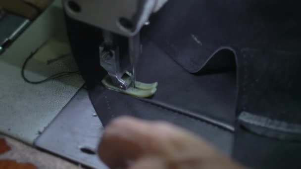 在缝纫机上缝制黑色皮夹克的裁缝师用银戒指对老手进行的特写。缝纫机制造皮革制品,沿着拉链缝线.慢动作. — 图库视频影像