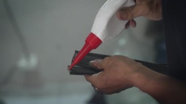 Eski elleri ceketin deri yüzeyine yapıştırıcı süren isimsiz misillemeler. Terzi imalatı sırasında hakiki deri eşyaların kollarını yapıştırmak. Özel giysiler hazırlıyorum..
