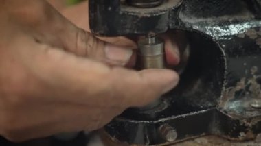 Ustanın eski ellerine yakın plan eski bir perçin montaj makinesine demir bir platform kurun. Terzi, perçinleme ürünleri üzerine el yapımı çalışmalar için stüdyoya özel bir parça yerleştirir..