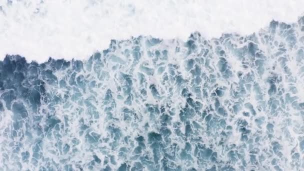 Güçlü okyanusun güzel dokusu, beyaz yıkamalı mavi renk dalgaları, fırtınalı bir günde muhteşem deniz gelgitlerinin havadan görüntüsü. İnsansız hava aracı Hint okyanusunda köpükle sörf yapıyor. Bali 'de büyük dalga — Stok video