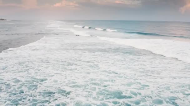 Повітряний вид зелених хвиль ламається, коли вони котяться до берега моря. Кадри дрона швидко літають над океанською енергією на мальовничому помаранчевому рожевому заході сонця на острові Балі. Біла мийка морської піни в Індійському океані.. — стокове відео