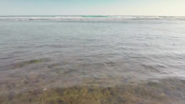 Aérea dinámica de arrecife marrón cerrado cubierto por la marea oceánica. Primer plano de las piedras de coral con algas que desaparecen bajo las olas con espuma blanca. Imágenes rápidas de vuelo de drones de olas azules en la playa en los trópicos — Vídeo de stock