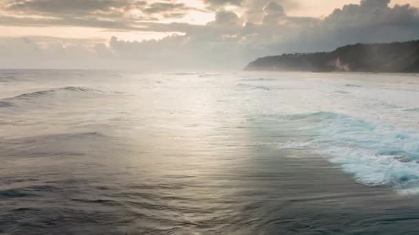 Luchtfoto van enorme golven die breken als ze naar de kust rollen. Drone vliegt snel op lage hoogte over oceaankracht bij een prachtige oranje-roze zonsondergang op Bali. Witte was van zeeschuim in de Indische oceaan. — Stockvideo