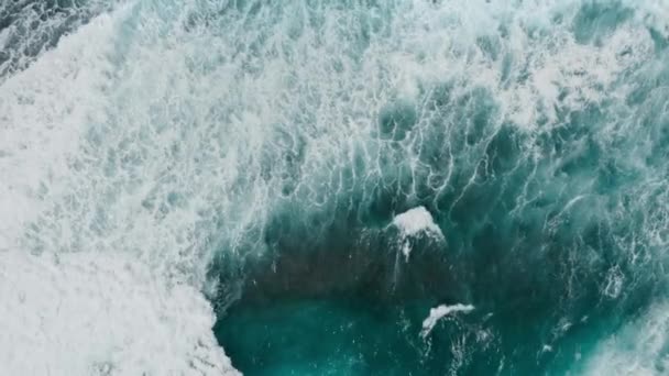 Zooms in on the big power ocean waves with white wash. Aerial top view footage of fabulous sea tide on a stormy day. Drone filming breaking surf with foam in the Indian ocean. Big swell in Bali. — Stock Video