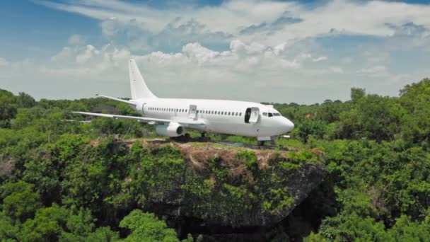 Flyby of airplane on edge of cliff in green tropical paradise. Abandoned aircraft in Bali island with panoramic ocean view at beach. Aerial view of aeroplane and hills. Panoramic. 4k — Stock Video