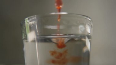 Parfümcü bardakta parfüm kokusuna yağ damlası döküyor. Portakal özü ve parfüm aroması kullanarak enfes bir koku yaratma süreci. Makro çekim yaptı. film tahıl dokusu.