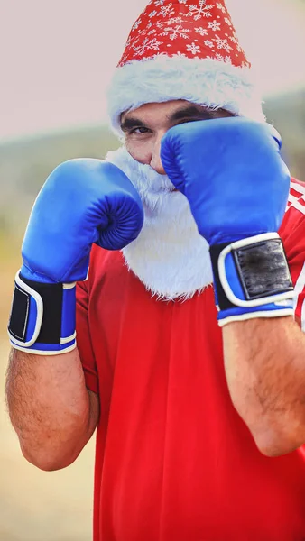 Homem desportivo vestindo roupas de Papai Noel e luvas de boxe ao ar livre — Fotografia de Stock