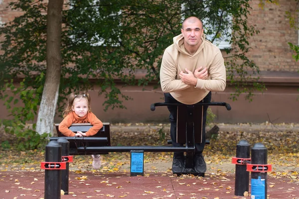 Uma menina caminha com o pai no parque infantil. Conceito de férias em família ativa saudável — Fotografia de Stock