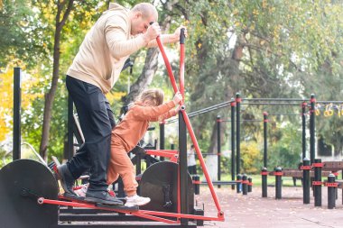 Aile çocukları spor sahasında yürürler ve aileleriyle egzersiz yaparlar.