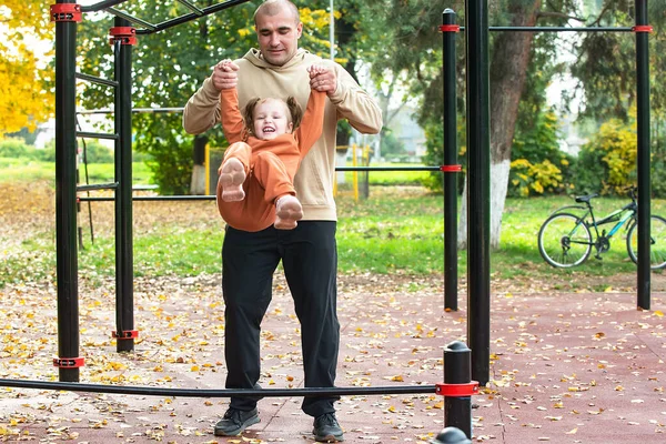 Aile çocukları spor sahasında yürürler ve aileleriyle egzersiz yaparlar.