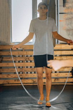 Gençler spor için spor salonuna gider ısınma turlarında ip atlarlar.