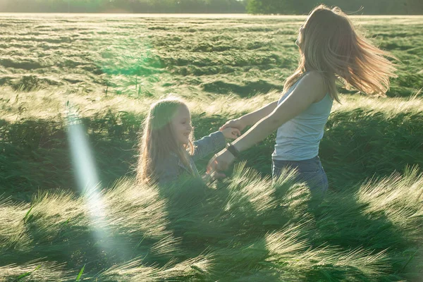 Family, mom and daughter enjoy a walk in the warm season on a field with green wheat — 스톡 사진