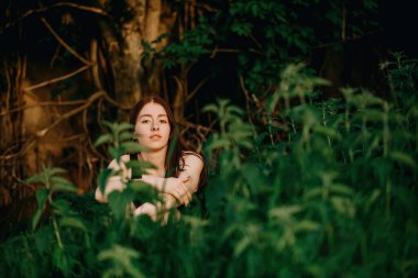 portrait of a beautiful young girl on a background of greenery and trees