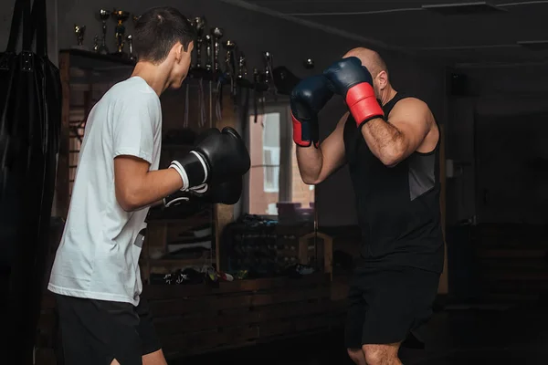 Trainer en bokser tiener doet een training in de sportschool — Stockfoto