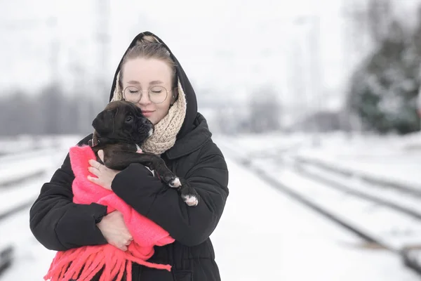 Portret van een mooie jonge vrouw met een Duitse bokser puppy op een winterwandeling — Stockfoto