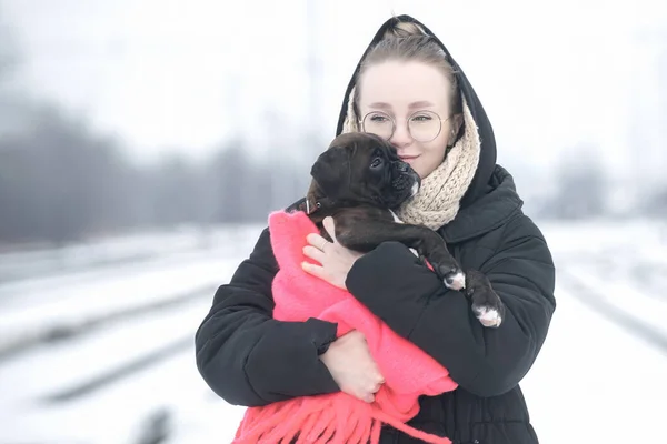 Portret pięknej młodej kobiety z niemieckim szczeniakiem bokserskim na zimowym spacerze — Zdjęcie stockowe