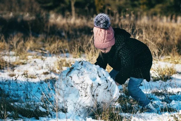 Kız kış parkında kar yağışı altında yürüyüşe çıkıyor.