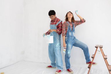 Yom-bear ve ekose gömlekli genç Asyalı çift Tayland 'da yeni bir renge boyamaya yardım ediyor.