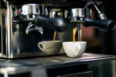 Kahve makinası kahve dükkanındaki tabakta cam bardağa ekspreso karıştırıyor. 