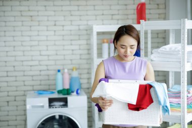 Kapı ve tuğla duvar arkasında temiz havlu yığını içinde genç mutlu bir hizmetçi. 