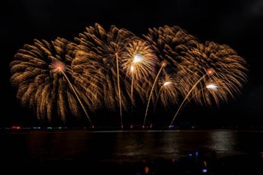 Uzun pozlu güzel kutlamalar gece denizde renkli havai fişekler ve Tayland 'ın karanlık arka planındaki su cephesini yansıtıyor.