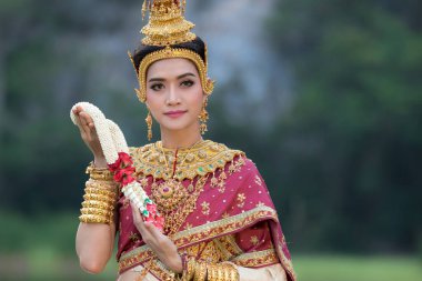 Tayland 'da güzel bir kadın. Geleneksel çelenkler takıyor. Bahçede gülümsüyor.