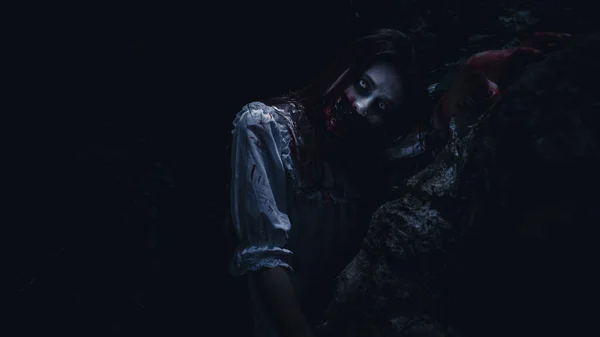 Portrait of young asian woman in white wedding dress make up ghost or zombie blood on  face, Horror genre with background dark scene movie in the park at night process, festival Halloween spacial at night scene concept