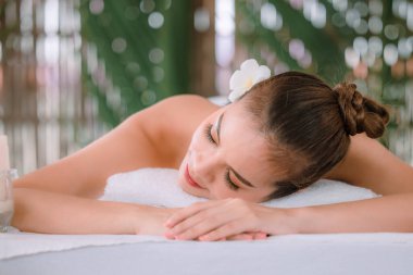 Güzel, genç Asyalı bir kadın masaj salonunda dinlenerek uyuyor. Kapat ve odaklanmış doğal ışık arkaplanını seç 